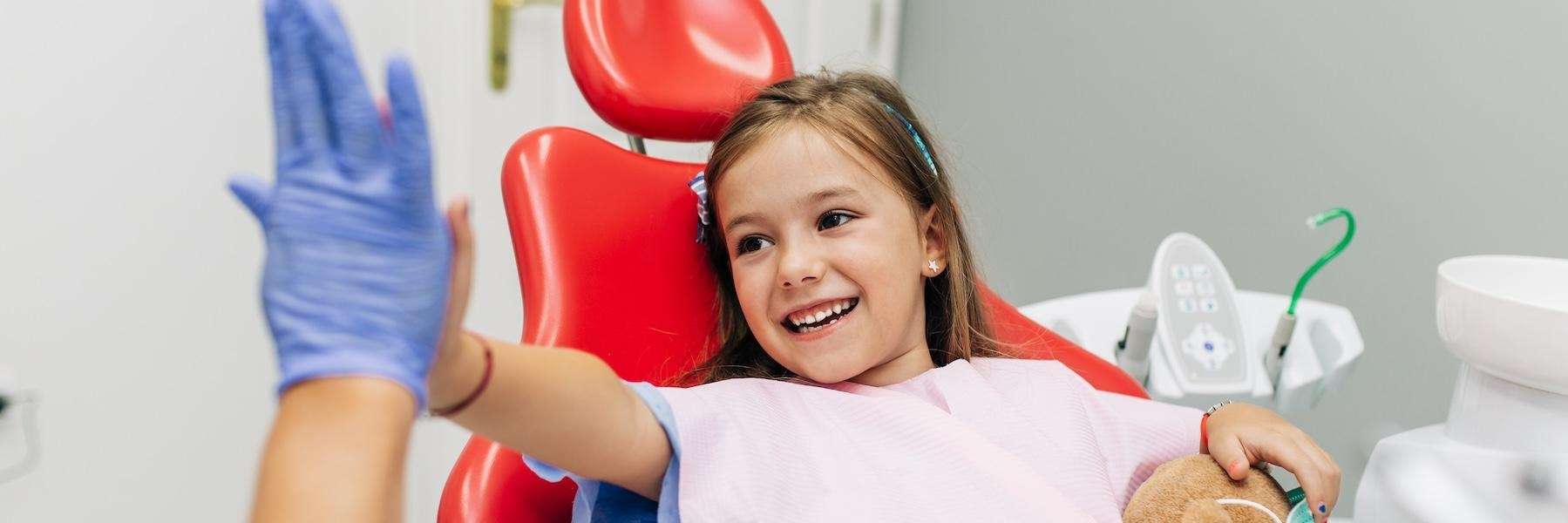 A little girl high fiving a dentist during a visit to a Children’s Dentist in Pikesville