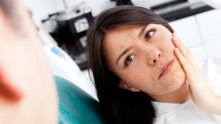 Patient holding her jaw due to tooth pains in Pikesville, MD