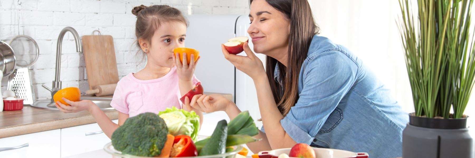 A woman with her kid eating fruits after getting Invisalign in Pikesville, MD